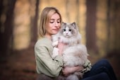 Luxury pet photography in san diego | kat de laet portraits 3 Young woman in a green blouse gently cradling a Siberian cat with soft golden light filtering through the trees. Fine art pet portrait by Kat De Laet, San Diego.