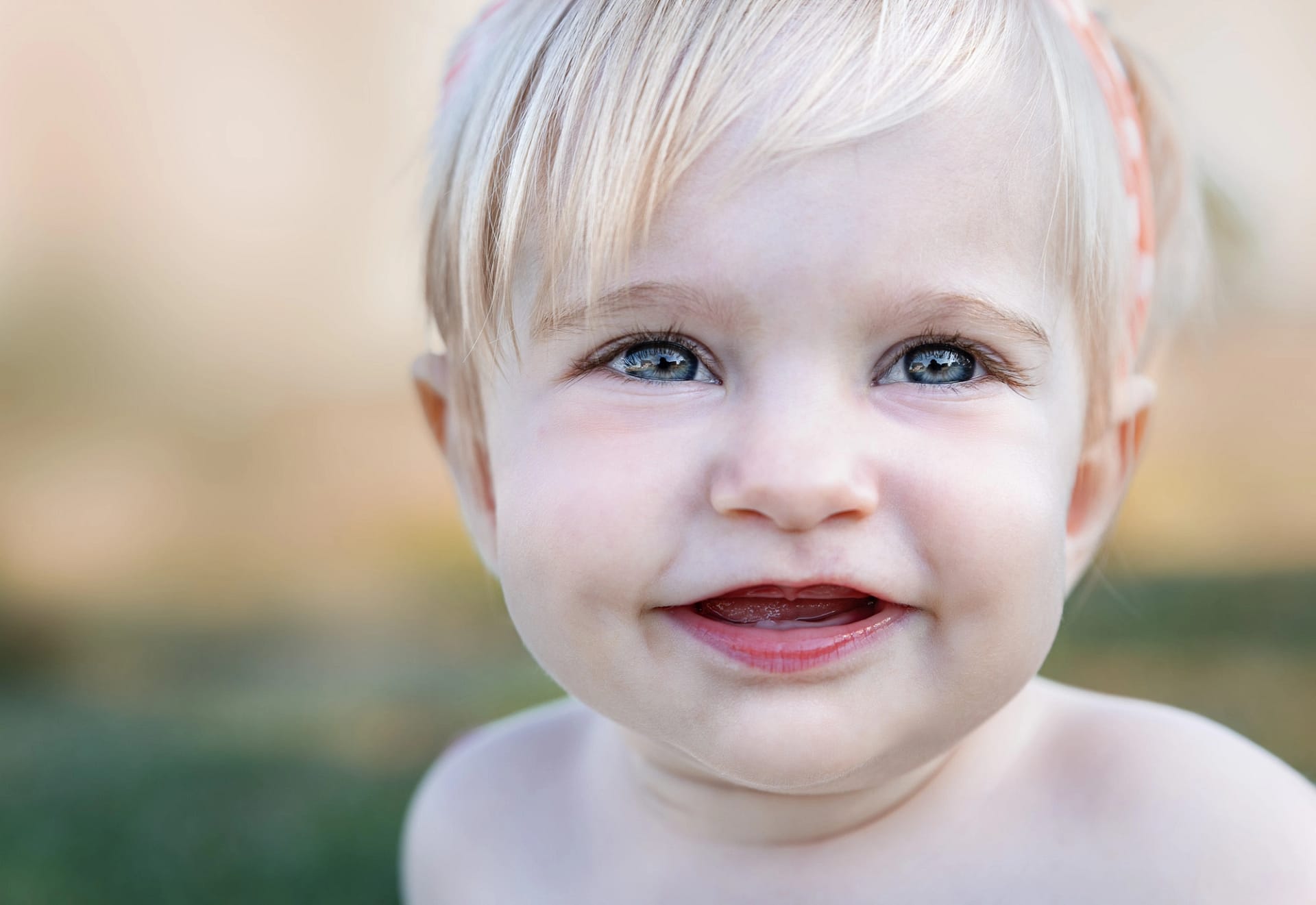 Baby with bright blue eyes smiling joyfully, conveying innocence and happiness.
