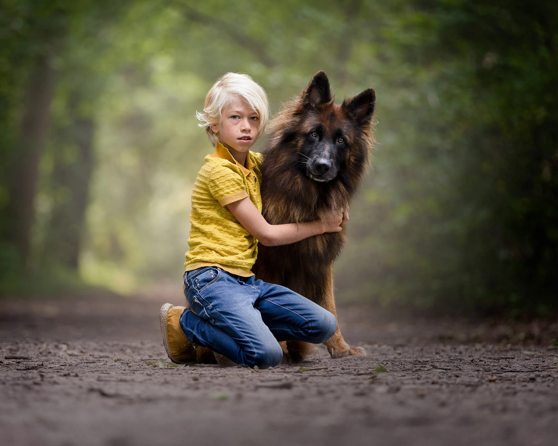 Young boy hugging a German Shepherd in a lush forest, illustrating the strong bond between child and dog.