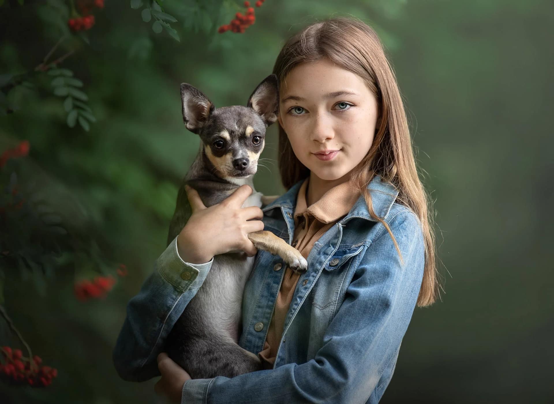 Young woman holding a small Chihuahua dog, both looking at the camera. Elegant pet and owner portrait by Kat De Laet, luxury pet photographer in San Diego.
