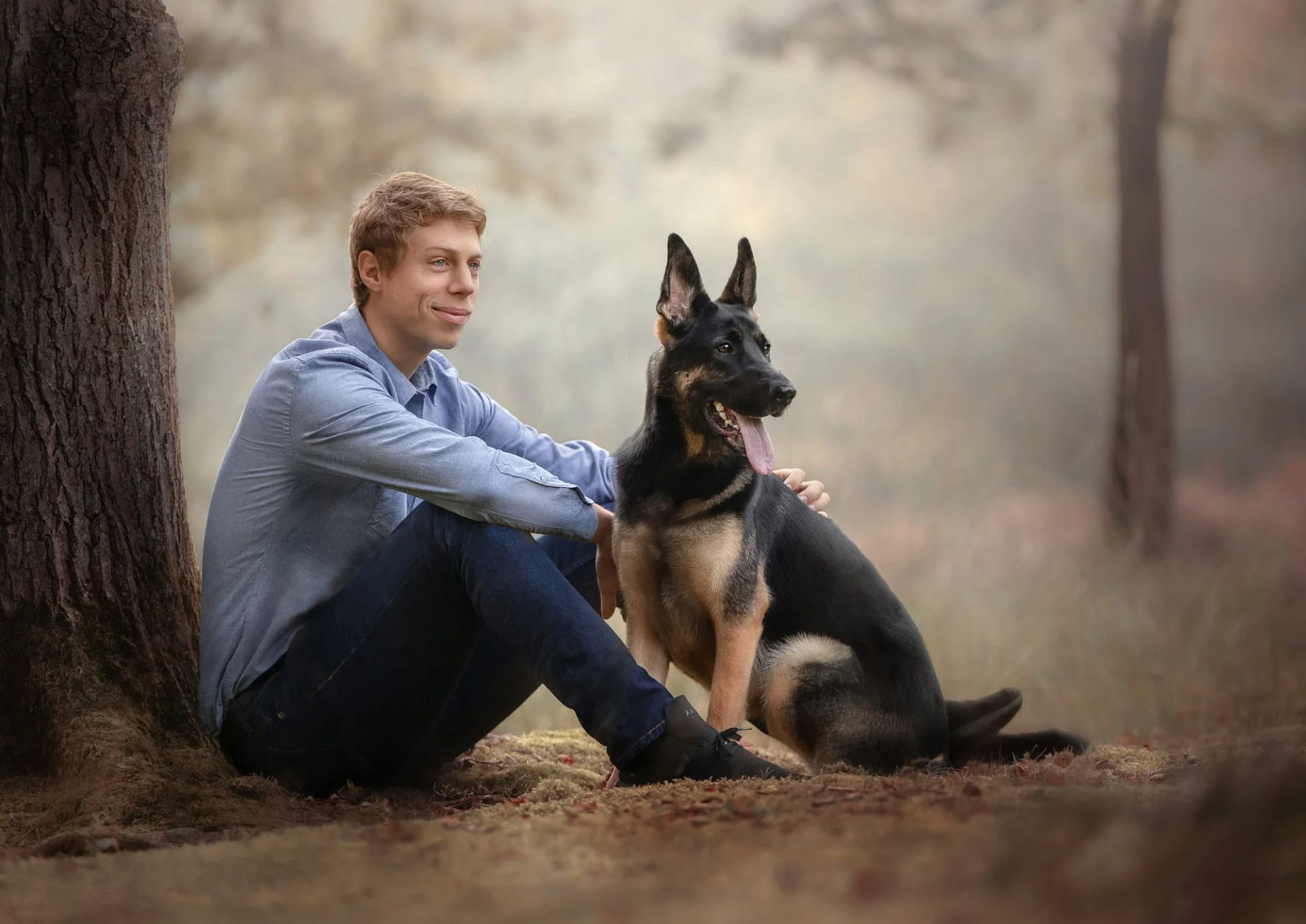Man sitting with his German Shepherd in a peaceful autumn park, both looking contemplative. Fine art dog photography by Kat De Laet, San Diego.